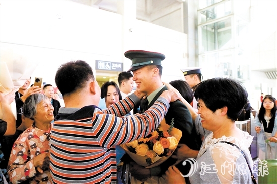 身著軍裝的返鄉(xiāng)退役士兵逐一出站，迎接他們的是鮮花與擁抱。