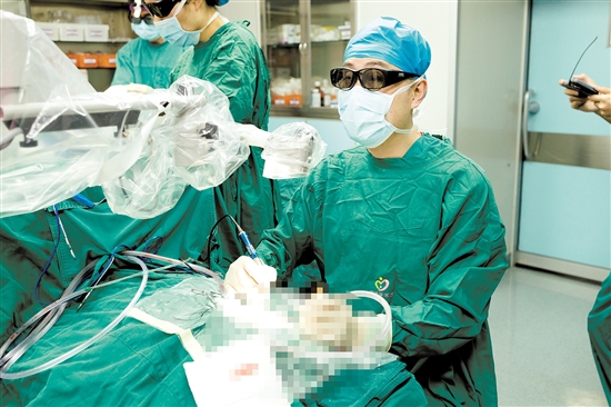 術(shù)中，醫(yī)生查看顯示屏，為患者植入人工耳蝸。