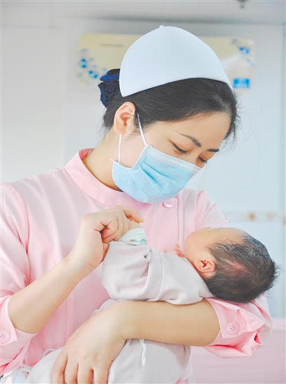 這是一雙托起生命的手。江門市中心醫(yī)院愛嬰?yún)^(qū)主管護(hù)師湯玲玲正在安撫哭鬧的寶寶。她一手環(huán)住襁褓，一手牽起寶寶的小手，動作舒緩而溫柔。在這里，生命的啼哭與溫柔的守護(hù)相遇，匯聚成世間至暖的力量。（林錦棠