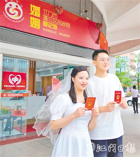 一對新人在蓬江區(qū)民政局婚姻登記處門口合影留念。