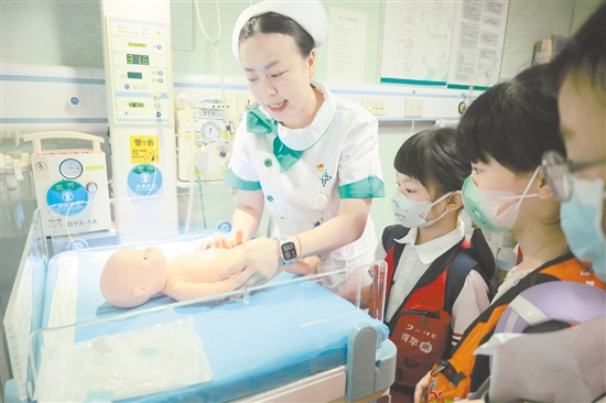 醫(yī)護人員為小記者演示新生兒輻射保暖臺的用途。