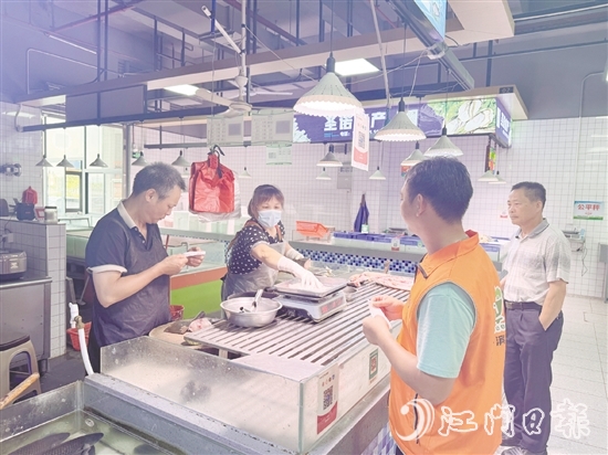 買菜易的平臺接單員李叔（橙色馬甲）正在魚攤旁等待取單。