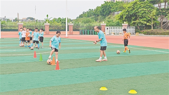 學(xué)生在教練的指導(dǎo)下學(xué)習(xí)足球技巧。