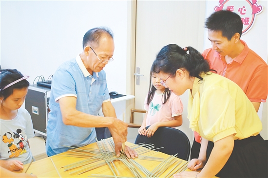 孩子和家長在手藝人的指導(dǎo)下學(xué)習(xí)編織小竹筐。