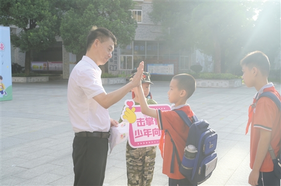 紫茶小學(xué)黨委書(shū)記譚國(guó)池與學(xué)生逐一擊掌。