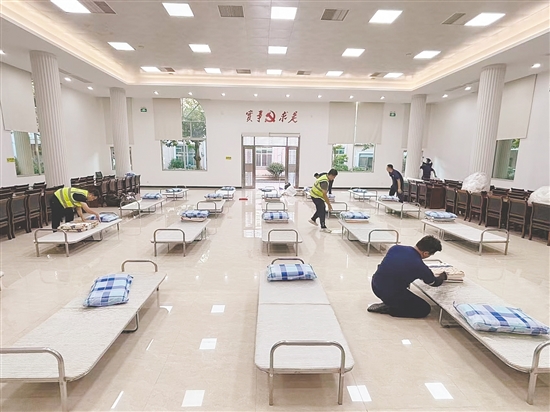 工作人員正在臨時(shí)庇護(hù)場(chǎng)所鋪設(shè)床位。