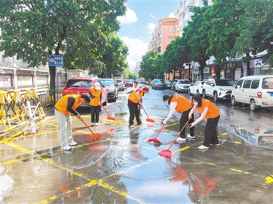 廣東江門中醫(yī)藥職業(yè)學院大學生志愿者合力清掃街道積水。