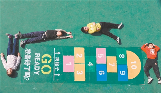 畫完“跳格子”后，學(xué)生們興奮地躺在地上合影。