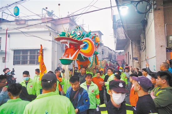 村民們高舉金龍，穿街過巷進(jìn)行巡游。