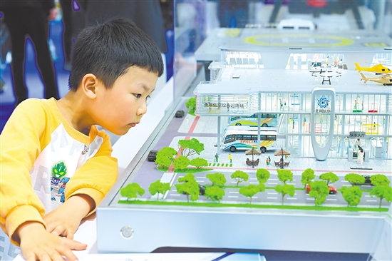 圖為當日，小朋友在第四屆科交會上觀看一款低空樞紐起降場模型。