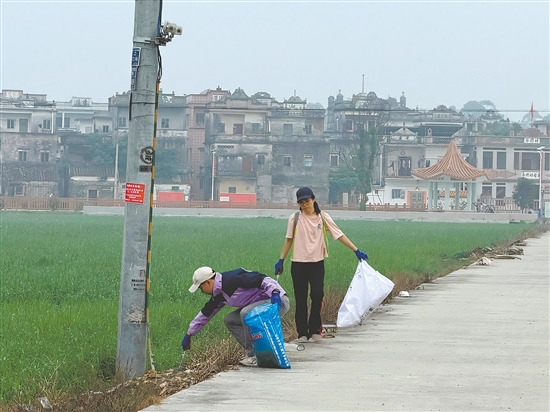 新村民走在鄉(xiāng)村道路清理垃圾。