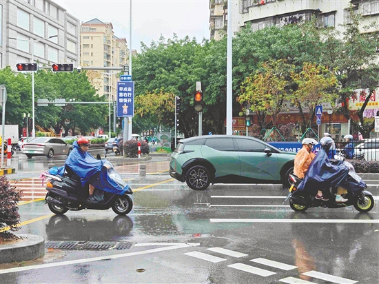 昨日，新會(huì)下起陣雨，市民紛紛穿上雨衣。