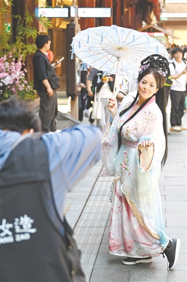 5月5日，外國游客在上海豫園商城內(nèi)體驗古風妝造旅拍。新華社發(fā)