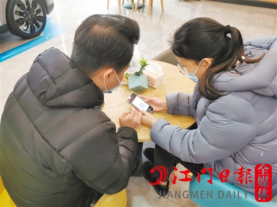 新能源汽車銷售人員協(xié)助車主用手機(jī)進(jìn)行投保新能源汽車險(xiǎn)。